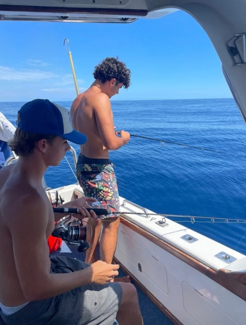 Cristiano fishing off the back of a boat on a clear day